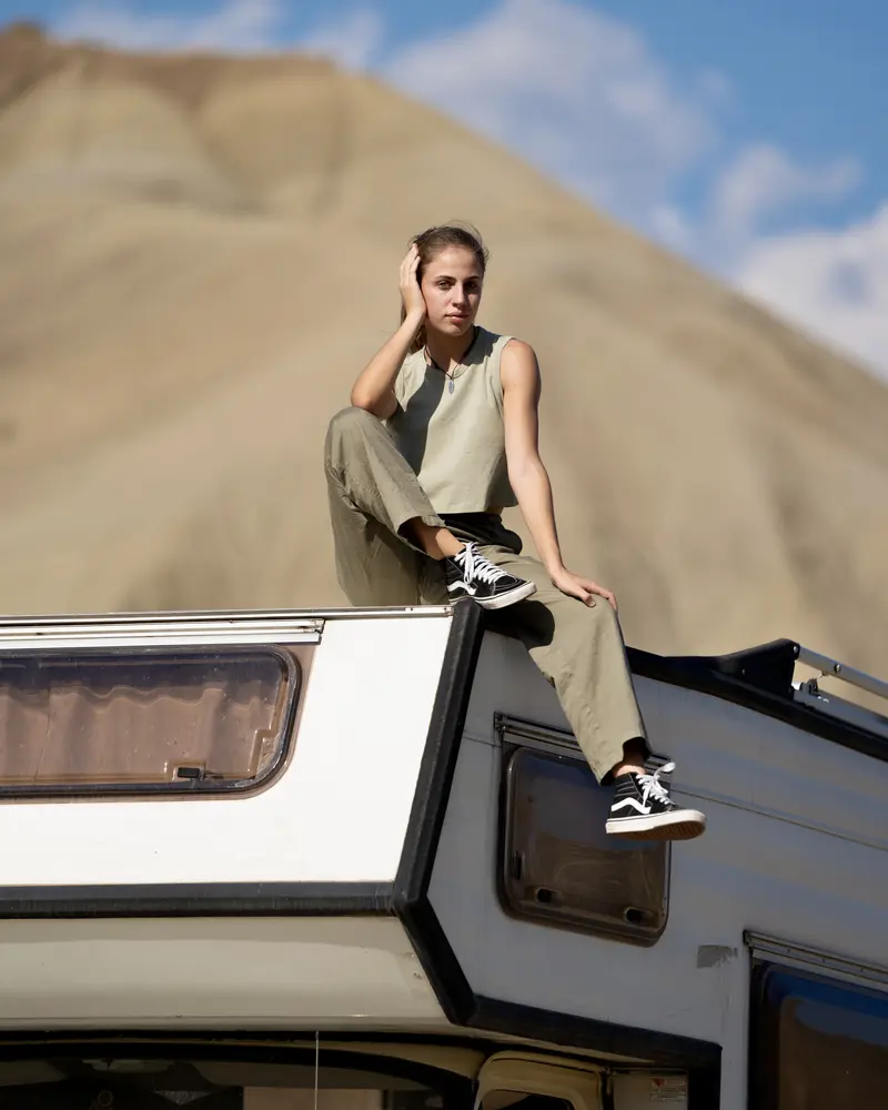 Noemi seduta sul tetto di un camper tra le dune